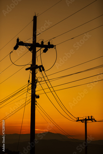 High voltage tower electric pole and wire at sunset or evening time.