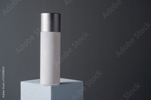 Cosmetic product in tube, bottle, lotion or serum and dried flowers on grey background. 
