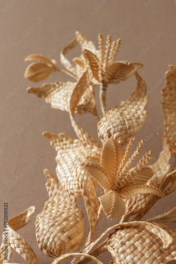 Obraz premium Decoration of straw on a beige background. Branch with leaves and flowers is made of straw. Decor. Closeup