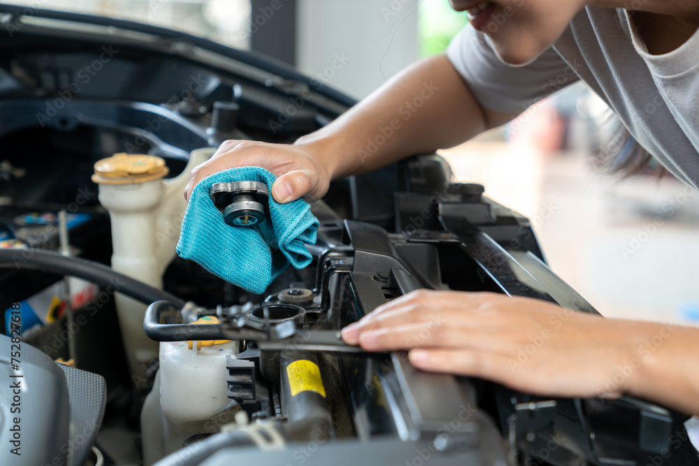 The young woman is opening cooling water, Check open radiator cap. The young woman is opening cooling water, Check open radiator cap.
