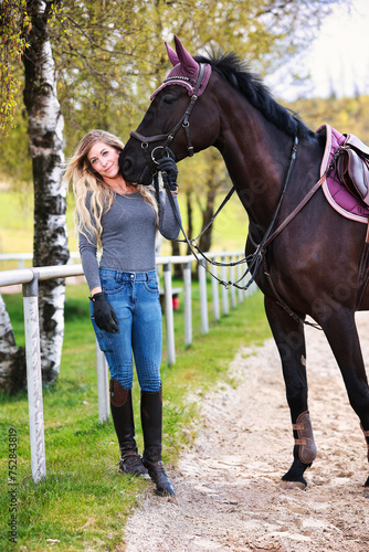 Young woman with long hair and blonde streaks, stands portraits with her horse.