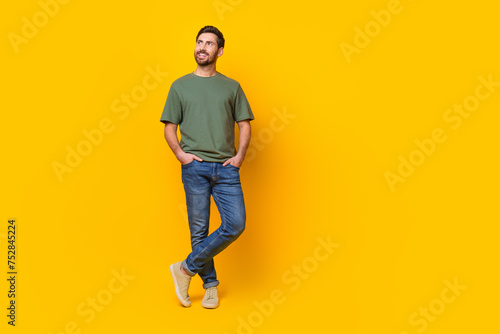 Full body photo of attractive young man hands pockets look empty space dressed stylish khaki clothes isolated on yellow color background