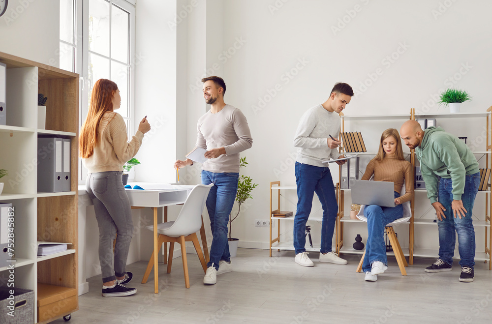 Group of company employees in a modern office workplace interior. Young people working together, doing their daily tasks, discussing work and using laptops. Business, lifestyle concept Group of company employees in a modern office workplace interior. Young people working together, doing their daily tasks, discussing work and using laptops. Business, lifestyle concept