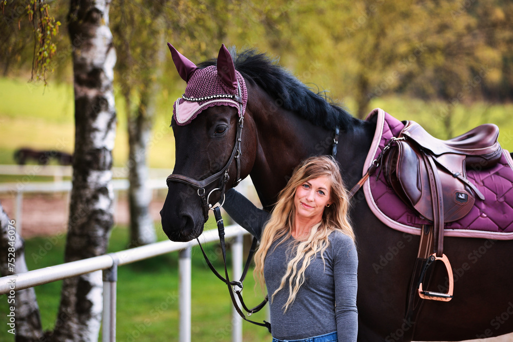 Obraz premium Young woman with long hair and blonde streaks, stands portraits with her horse.