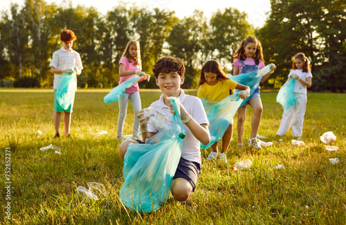 Children volunteers collect garbage to make the area a nice place at a social charity ecology event Happy little school kids clean park ground from human waste that people throw not reaching trash bin