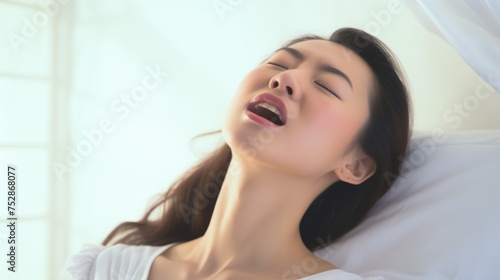 Woman's face during an orgasm in bed. Women's pleasure. A beautiful Asian female with soft skin is enjoying and feels good.
