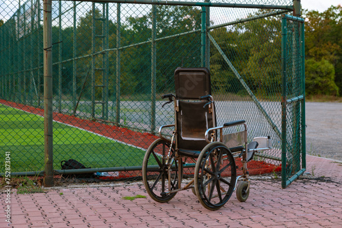 An empty wheelchair near the open gate of the soccer or football field. photo