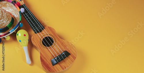 Cinco de Mayo holiday background, maracas, mexican hat and guitar on orange background. © Marcela Ruty Romero