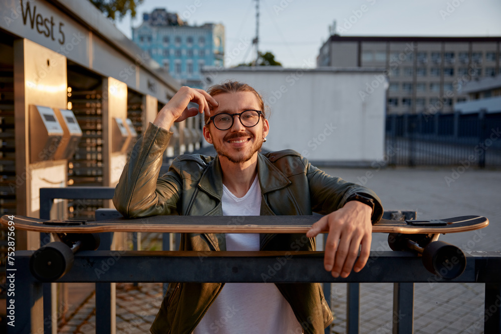 Portrait of happy smiling skateboarder hipster guy resting outdoors Portrait of happy smiling skateboarder hipster guy resting outdoors