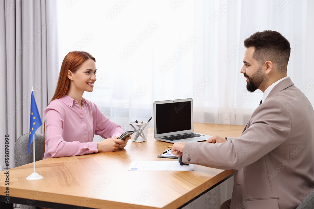 Immigration to European Union. Embassy worker approving visa application form to woman in office Immigration to European Union. Embassy worker approving visa application form to woman in office