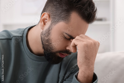 Man suffering from headache at home, closeup