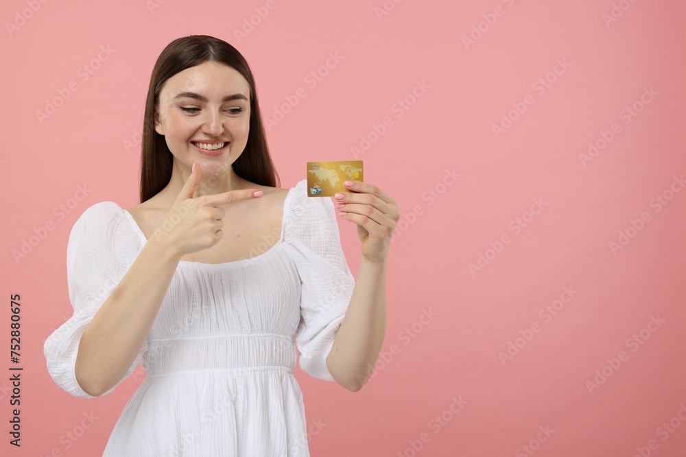 Happy woman pointing at credit card on pink background, space for text Happy woman pointing at credit card on pink background, space for text