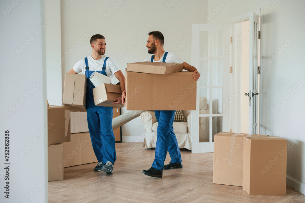 Boxes in hands. Two moving service employees in a room Boxes in hands. Two moving service employees in a room