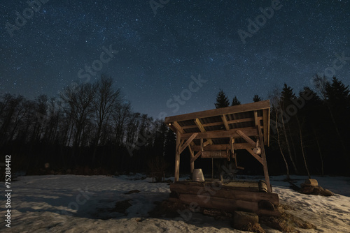 Night scene, landscape astrophoto, old well in the forest with a starry sky.
