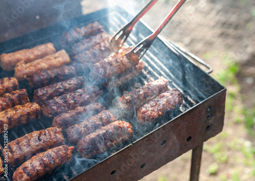 small Romanian minced meatrolls called mici or mititei, similar to serbian cevapi, fresh balkan skinless sausages, cooked outside on the barbecue photo