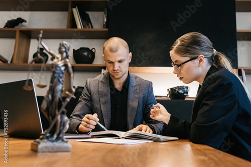 A lawyer meets with a new client. A young male lawyer in a suit sits at an office desk, shares legal advice, explains the inheritance process, tries to help. Legal advice concept