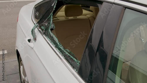 A close-up of a shattered window of a car parked in a lot, illustrating an act of vandalism and the resulting damage photo