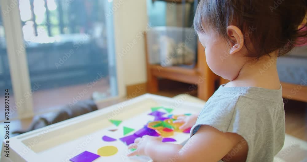 Over-the-shoulder view of a toddler playing with translucent colored shapes on a light table, showcasing a bright, engaging activity that stimulates sensory and cognitive development Over-the-shoulder view of a toddler playing with translucent colored shapes on a light table, showcasing a bright, engaging activity that stimulates sensory and cognitive development