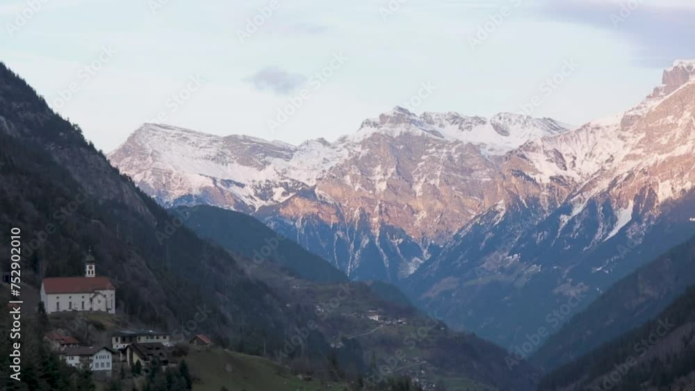 Alpine village nestled in valley with snow-capped mountains at dusk, serene landscape Alpine village nestled in valley with snow-capped mountains at dusk, serene landscape