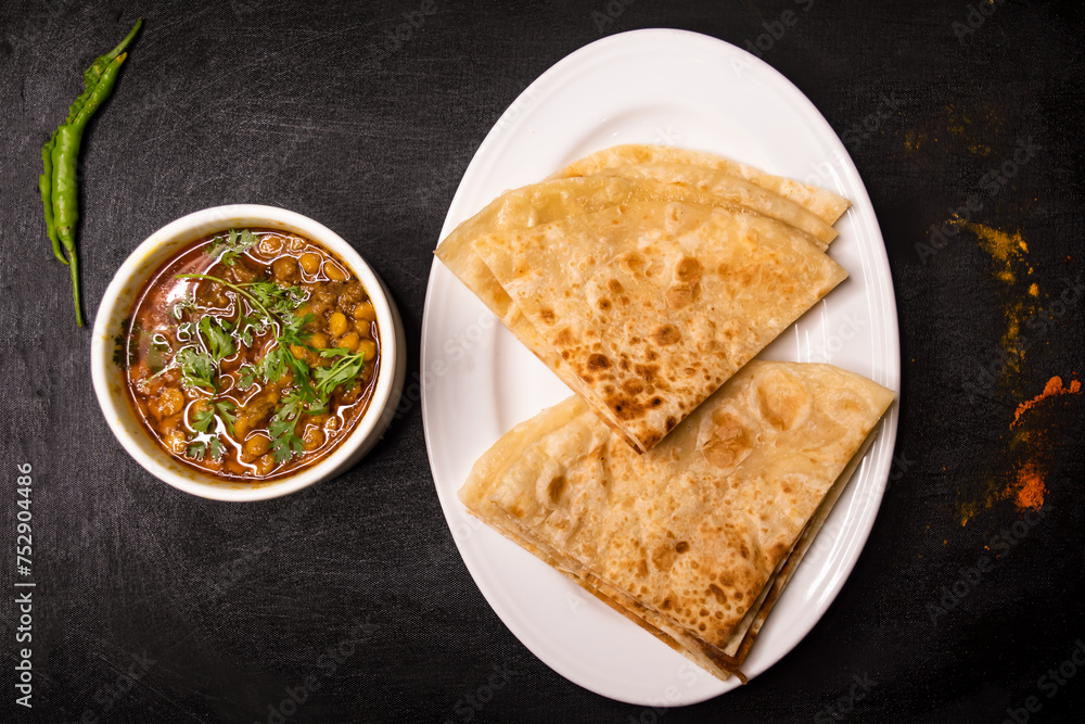 paratha with dal chana or chanay served in dish isolated on dark background top view indian spices, bangladeshi and pakistani food paratha with dal chana or chanay served in dish isolated on dark background top view indian spices, bangladeshi and pakistani food