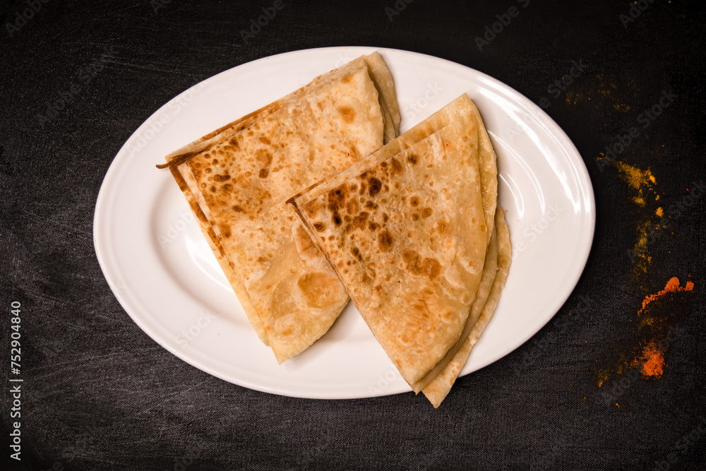 Paratha Sliced served in dish isolated on dark background top view indian spices, bangladeshi and pakistani food