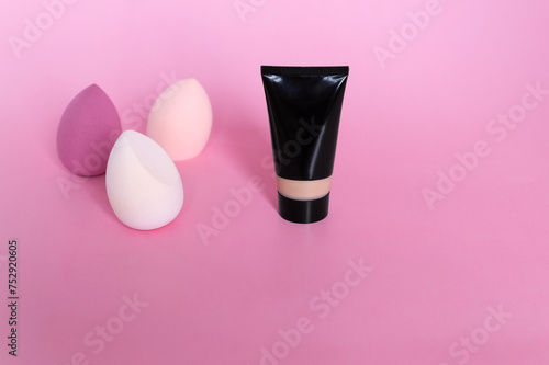 Tone cream with makeup sponges on pink background. Copy space. Cosmetic tool for beautiful skin tone. © Maria