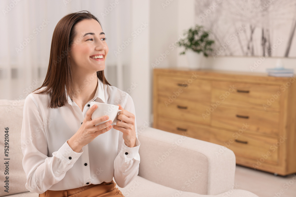Beautiful woman with cup of coffee smiling in room, space for text Beautiful woman with cup of coffee smiling in room, space for text