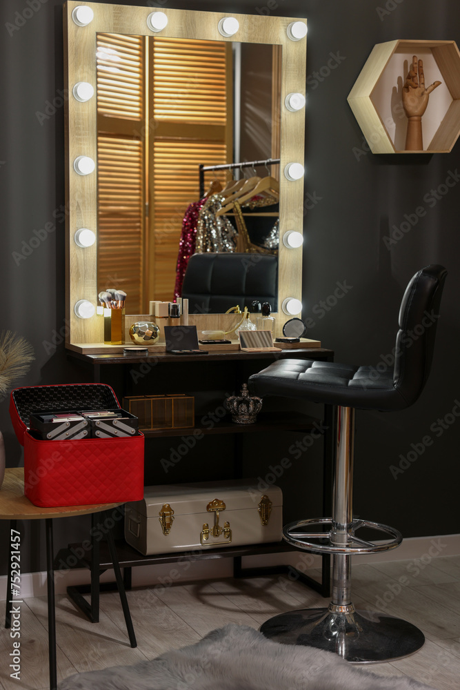 Makeup room. Stylish mirror near dressing table with beauty products and chair indoors Makeup room. Stylish mirror near dressing table with beauty products and chair indoors