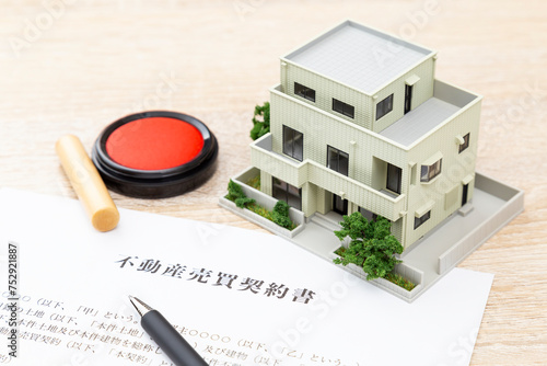 Foto 机に住宅模型と契約書