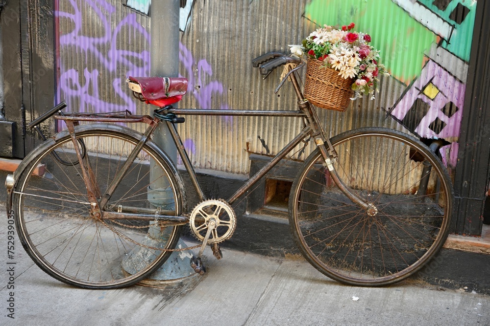 Rustic Vintage Pushbike with flowers in a basket leaning against a corrugated metal wall. 