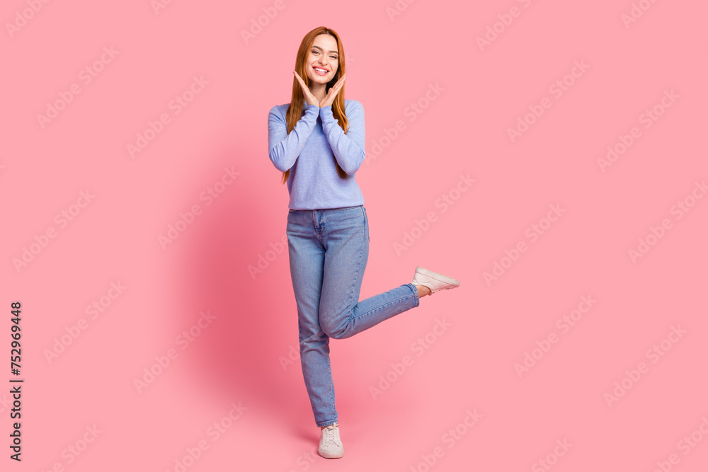 Full size photo of nice pretty woman dressed blue shirt jeans hold palms near face stand on one foot isolated on pink color background Full size photo of nice pretty woman dressed blue shirt jeans hold palms near face stand on one foot isolated on pink color background