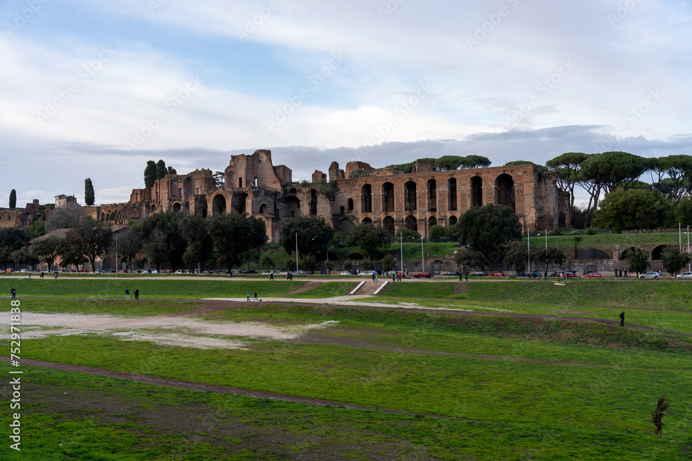 A large building with a lot of arches and a grassy field in the background