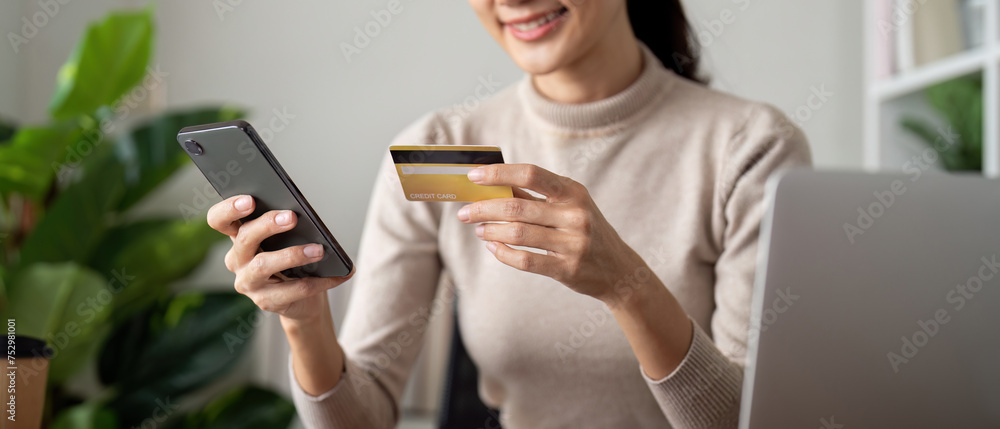 Online payment, Woman hands holding a credit card and using smartphone for online shopping at home Online payment, Woman hands holding a credit card and using smartphone for online shopping at home