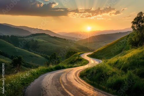 A winding road in a mountainous landscape during sunset. © ParinApril