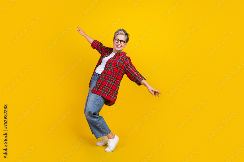 Full body photo of positive pretty lady stand tiptoes dancing empty space isolated on yellow color background