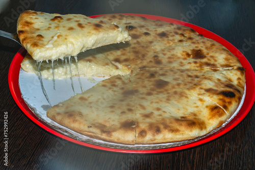 There is an Ossetian pie with cheese on the table in a plate. Cheese pie made from organic products. National dishes. photo