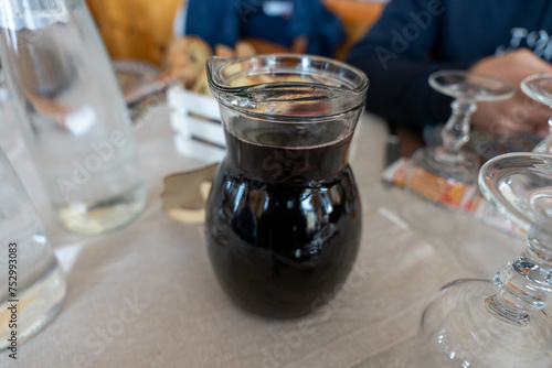 A pitcher of dark liquid sits on a table with a few other items