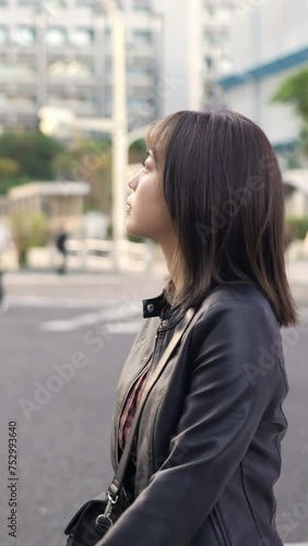 Vertical video of a young Japanese Okinawan woman in her 20s walking on Kokusai Street, a tourist attraction in Naha City, Okinawa Prefecture 沖縄県那覇市の観光名所の国際通りで若い２０代の日本人沖縄県民女性が歩く縦長動画 photo