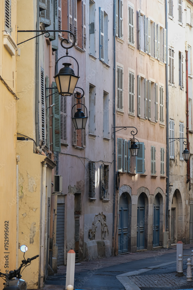 Romantic backstreet road alley in historic old town downtown Toulon, France with Mediterranean style house building facades and old little piazzas fountains picturesque city scenery	