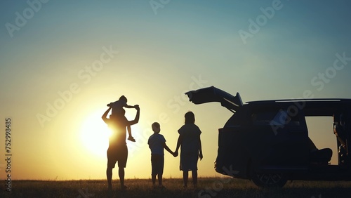 family traveling by car. family watching the sunset silhouette next to the car in the park. happy family kid dream concept. people in the park. family car camping resting lifestyle in nature