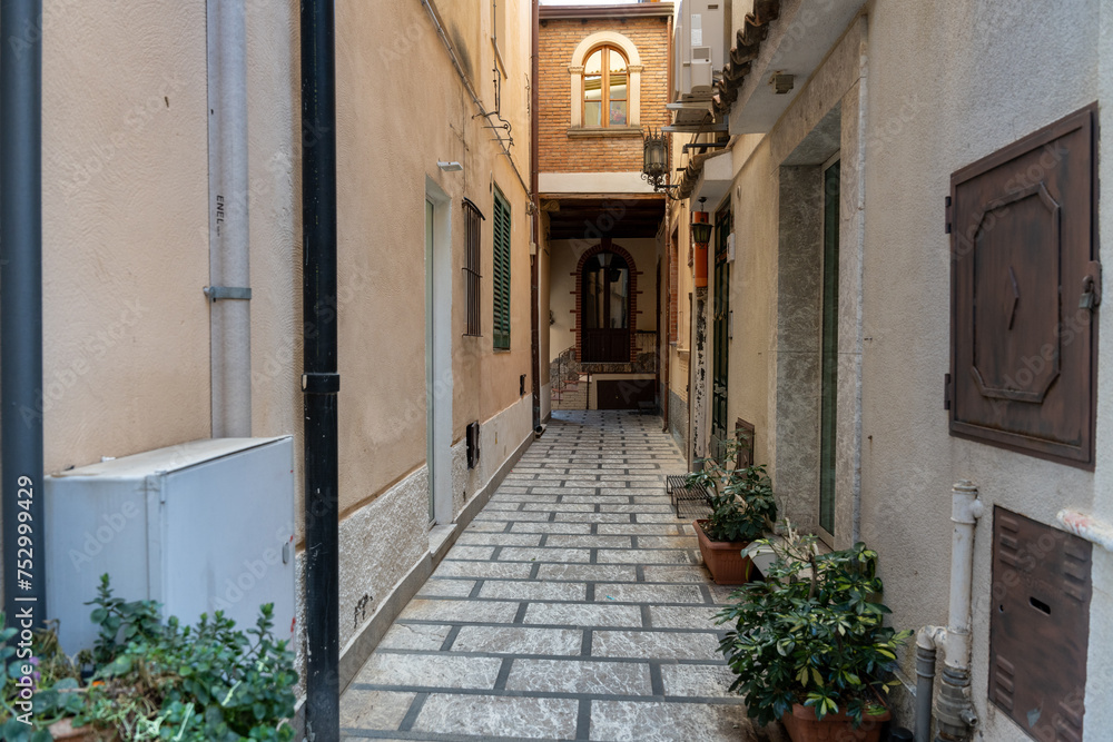 A narrow alleyway with a white building on the left