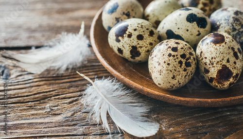 Quail eggs and feathers on a wooden table.