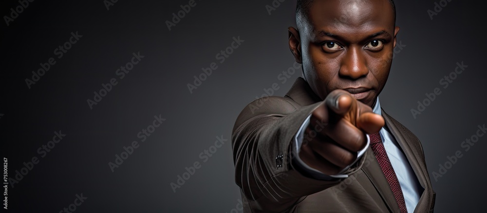 Confident businessman in a suit pointing directly at the camera Confident businessman in a suit pointing directly at the camera