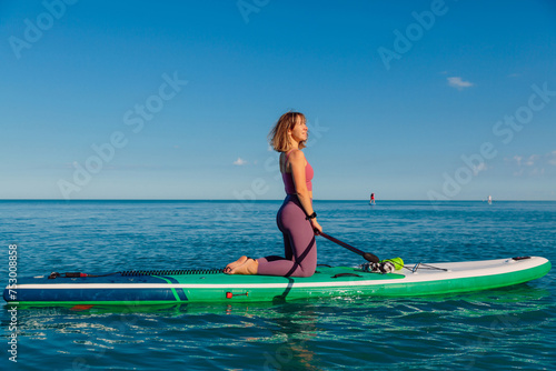 Woman on stand up paddle board, quiet ocean on sunny summer day. Relaxing on sea © artifirsov