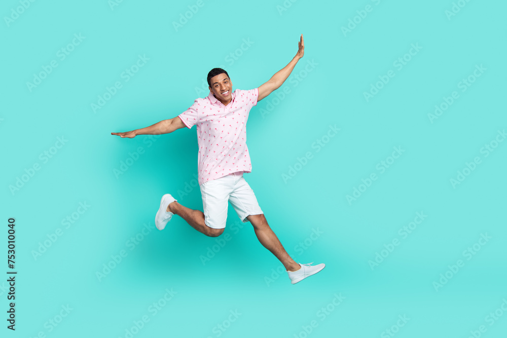 Full size photo of carefree optimistic guy dressed t-shirt white shorts flying hold palms like wings isolated on teal color background
