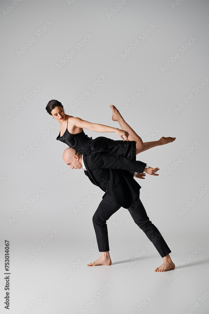 Graceful dance, young couple performing an acrobatic routine in a studio setting with grey backdrop