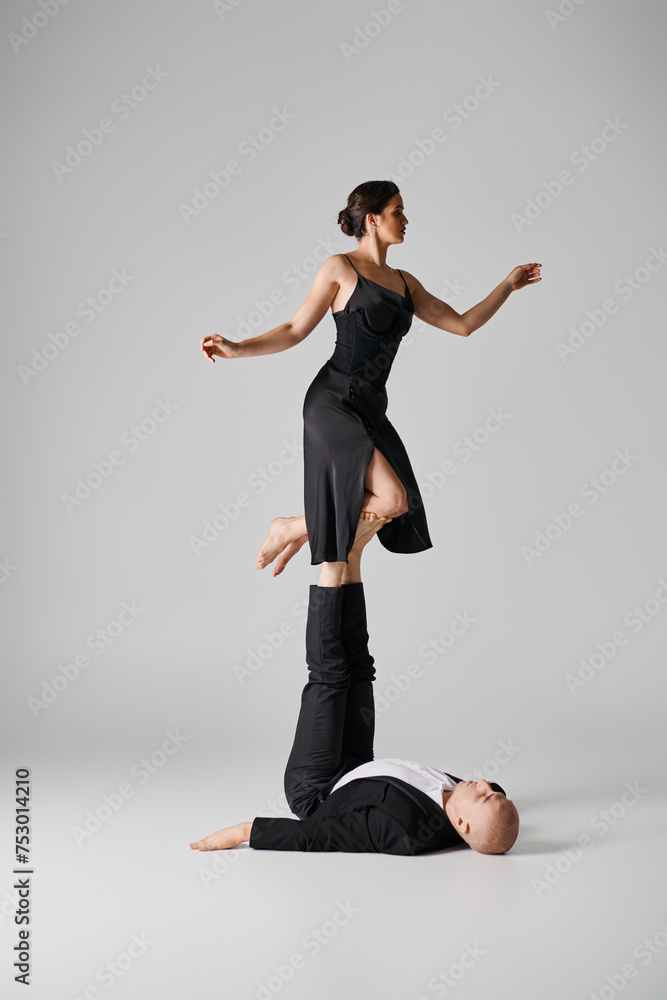 athletic duo, couple of acrobats performing balance act in a studio setting with grey backdrop