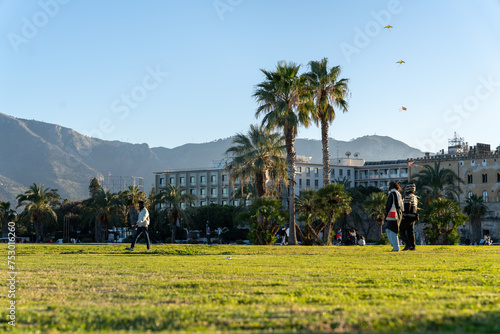 A group of people are walking in a park with palm trees in the background
