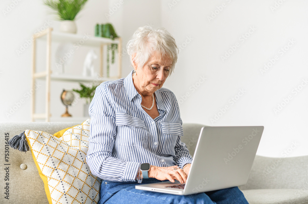 Smiling mature grey senior woman sit on sofa at home Smiling mature grey senior woman sit on sofa at home