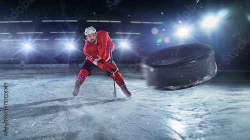Ice hockey rink arena with professional player shooting the puck with hockey stick. Focus on 3D flying puck with blur motion effect.